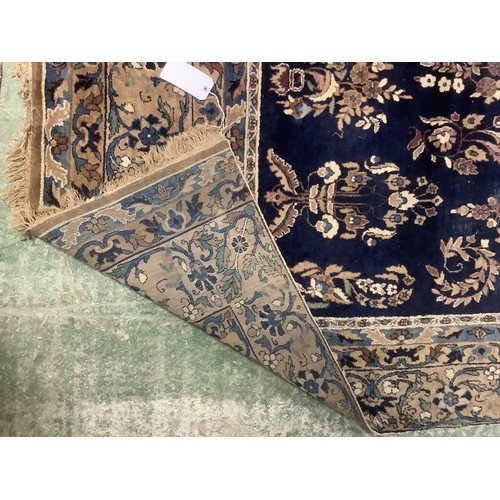 384 - A large Persian style blue ground rug, notable all over wear 255 cm x 404 cm