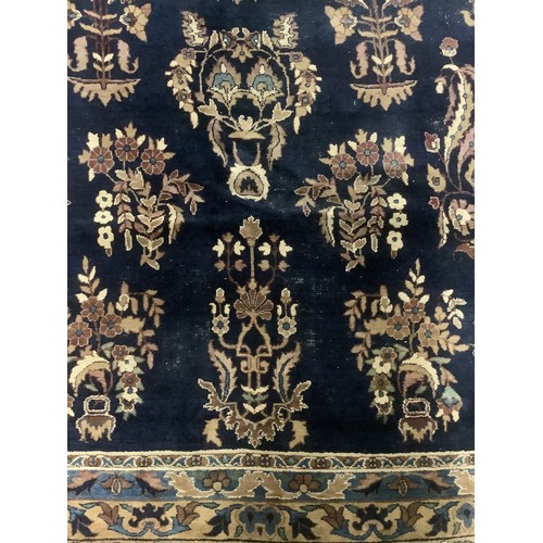 384 - A large Persian style blue ground rug, notable all over wear 255 cm x 404 cm