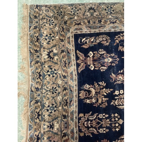 384 - A large Persian style blue ground rug, notable all over wear 255 cm x 404 cm