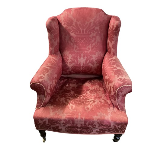 561 - Red upholstered wing back arm chair to turned legs and brass castors 88 cm H 76 cm W x 68n cm D at b... 