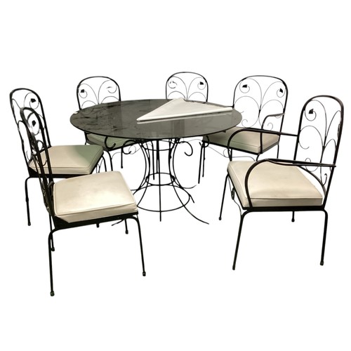 569 - A circular black glass conservatory table  with 6 matching chairs and cushions