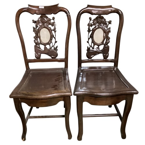 576 - A pair of hardwood oriental style chairs, with solid seat and carved back, and central oval stone pa... 