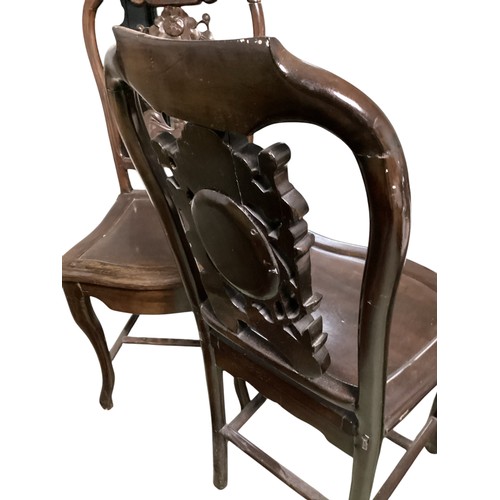 576 - A pair of hardwood oriental style chairs, with solid seat and carved back, and central oval stone pa... 