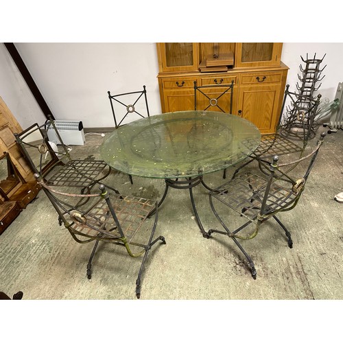 568 - A circular glass garden table with heavy iron base, and 6 matching chairs, as found with some wear