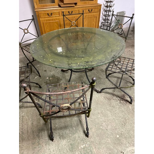 568 - A circular glass garden table with heavy iron base, and 6 matching chairs, as found with some wear