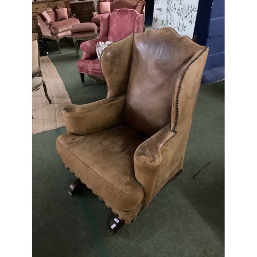 566 - A good, very worn, leather studded wing back rocking (sprung) arm chair, 106 cm H. Condition: much a... 