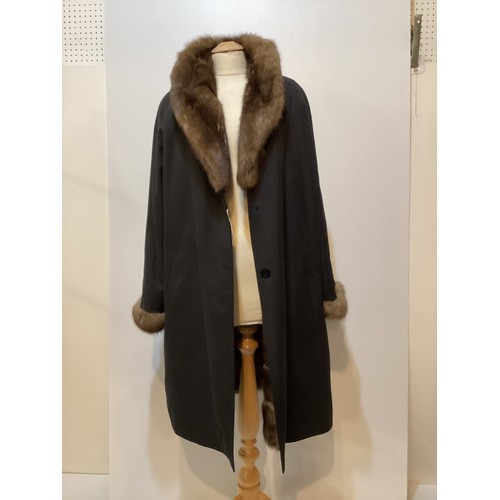 79 - A black 3/4 length black raincoat with  fur lining and fur collar and cuffs.