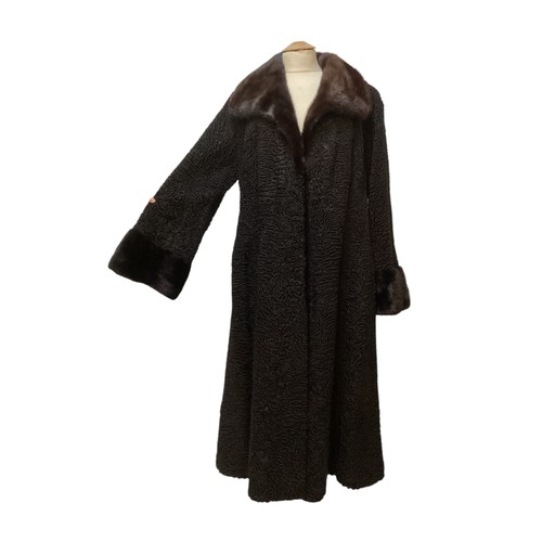 93 - A long, black Astrakhan coat with brown fur collar and cuffs, labelled SWAKARA. Condition, no sign o... 