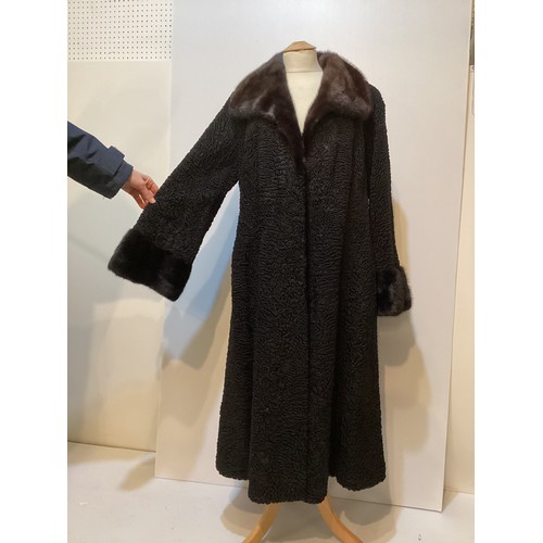 93 - A long, black Astrakhan coat with brown fur collar and cuffs, labelled SWAKARA. Condition, no sign o... 