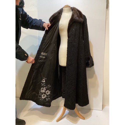 93 - A long, black Astrakhan coat with brown fur collar and cuffs, labelled SWAKARA. Condition, no sign o... 