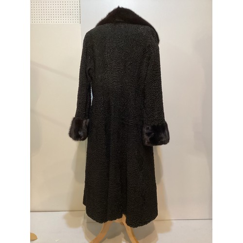 93 - A long, black Astrakhan coat with brown fur collar and cuffs, labelled SWAKARA. Condition, no sign o... 