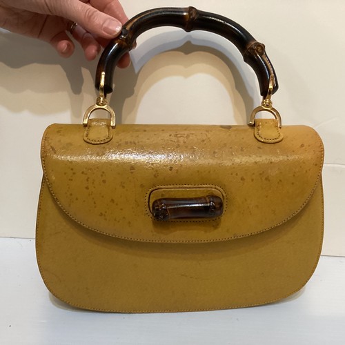 71 - Two GUCCI leather handbags with bamboo handle and fastening. Yellow with Gucci metal zip pull and nu... 