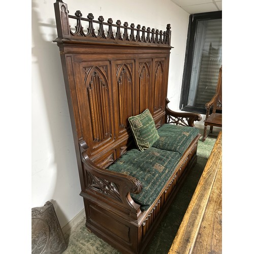 600 - A large gothic style high backed bench, with rising lid seat, and four decorative arched panels to b... 