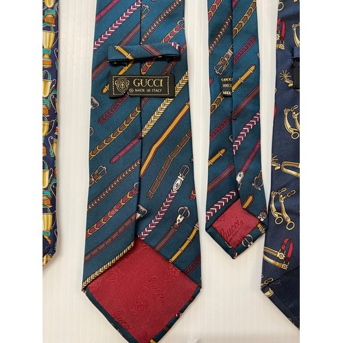 235 - Three Gucci silk ties - green background with belts, navy background with gold cups, navy background... 