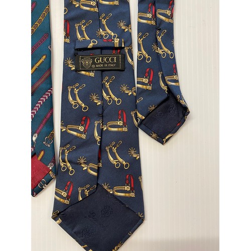 235 - Three Gucci silk ties - green background with belts, navy background with gold cups, navy background... 