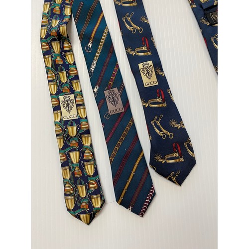 235 - Three Gucci silk ties - green background with belts, navy background with gold cups, navy background... 