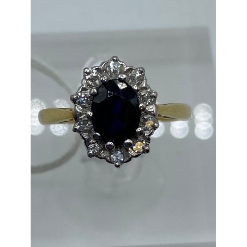 276 - An 18ct gold sapphire and diamond ring, central oval free cut sapphire, with a surround of 10 single... 