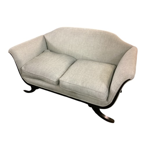 643 - A light blue upholstered camel back shaped two seater sofa, with wooden outswept legs to brass paw f... 