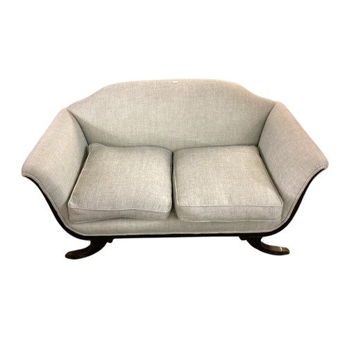 643 - A light blue upholstered camel back shaped two seater sofa, with wooden outswept legs to brass paw f... 