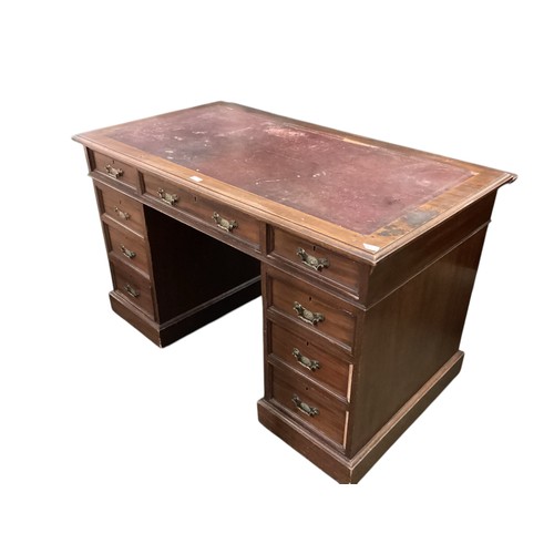 641 - A pine nine drawer pedestal desk with red leather top and brass drop handles. Much wear, see all pho... 