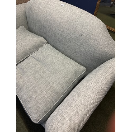 643 - A light blue upholstered camel back shaped two seater sofa, with wooden outswept legs to brass paw f... 