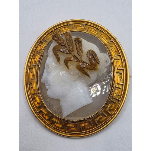 3 - Elena Pistrucci (1822-1886) An unmarked yellow metal hardstone cameo brooch with Greek key oval surr... 