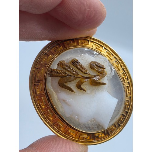 3 - Elena Pistrucci (1822-1886) An unmarked yellow metal hardstone cameo brooch with Greek key oval surr... 