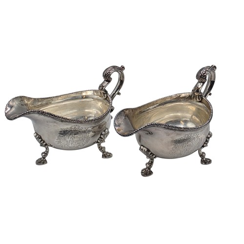 11 - A pair of sterling silver sauceboats with cast beaded rim and scroll handles. With chased armorial o... 