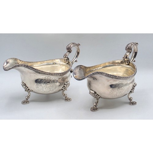 11 - A pair of sterling silver sauceboats with cast beaded rim and scroll handles. With chased armorial o... 