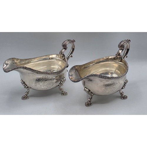 11 - A pair of sterling silver sauceboats with cast beaded rim and scroll handles. With chased armorial o... 