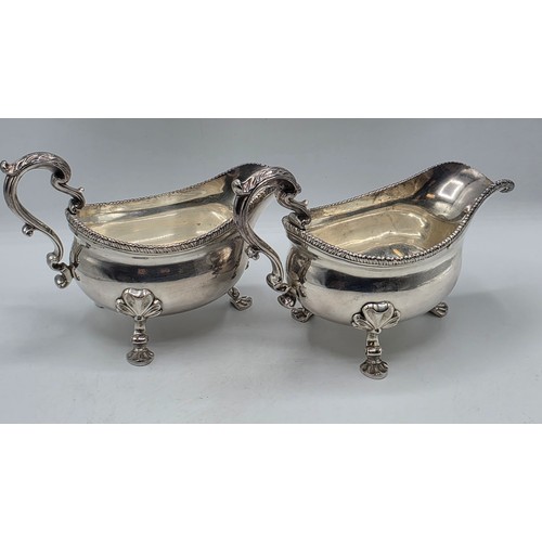 11 - A pair of sterling silver sauceboats with cast beaded rim and scroll handles. With chased armorial o... 