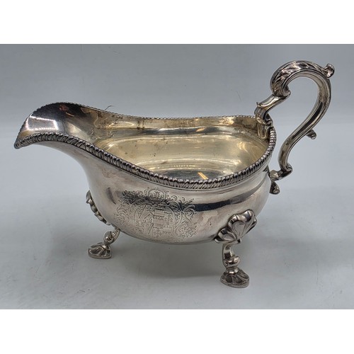 11 - A pair of sterling silver sauceboats with cast beaded rim and scroll handles. With chased armorial o... 