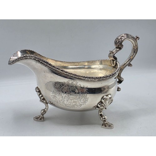 11 - A pair of sterling silver sauceboats with cast beaded rim and scroll handles. With chased armorial o... 