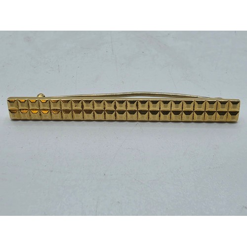 12 - An 18ct gold bar brooch with geometric textured design. 9.9g.