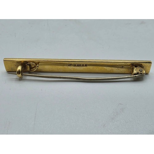 12 - An 18ct gold bar brooch with geometric textured design. 9.9g.