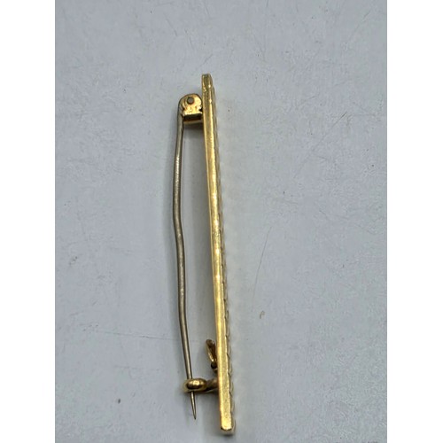 12 - An 18ct gold bar brooch with geometric textured design. 9.9g.
