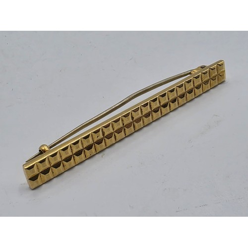 12 - An 18ct gold bar brooch with geometric textured design. 9.9g.
