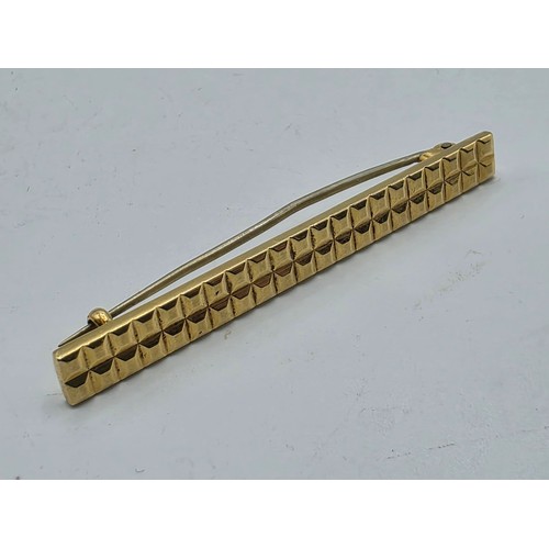 12 - An 18ct gold bar brooch with geometric textured design. 9.9g.