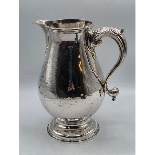 17 - A sterling silver hand planished water jug on circular stepped foot with scroll handle by SJ Phillip... 
