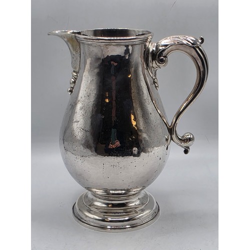 17 - A sterling silver hand planished water jug on circular stepped foot with scroll handle by SJ Phillip... 