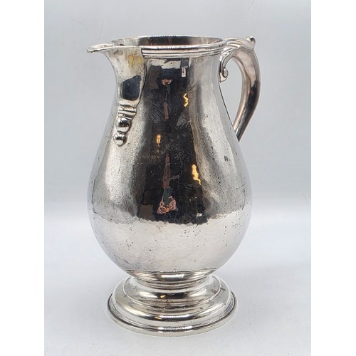 17 - A sterling silver hand planished water jug on circular stepped foot with scroll handle by SJ Phillip... 