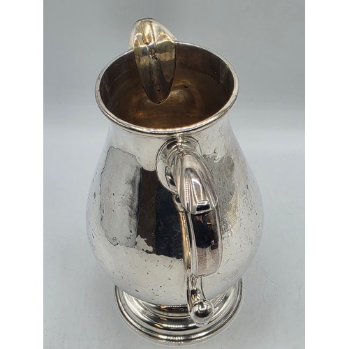 17 - A sterling silver hand planished water jug on circular stepped foot with scroll handle by SJ Phillip... 