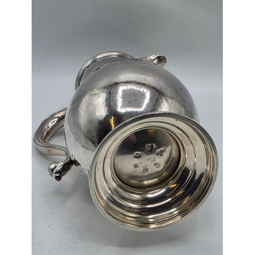 17 - A sterling silver hand planished water jug on circular stepped foot with scroll handle by SJ Phillip... 