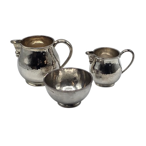 18 - Two matching sterling silver hand planished jugs together with matching hand planished sterling silv... 