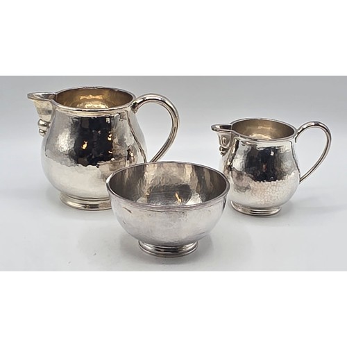 18 - Two matching sterling silver hand planished jugs together with matching hand planished sterling silv... 