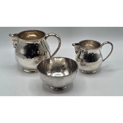 18 - Two matching sterling silver hand planished jugs together with matching hand planished sterling silv... 