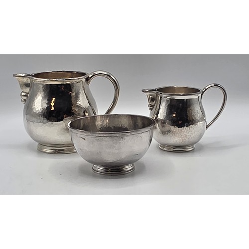 18 - Two matching sterling silver hand planished jugs together with matching hand planished sterling silv... 