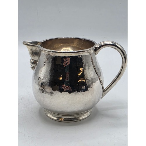 18 - Two matching sterling silver hand planished jugs together with matching hand planished sterling silv... 