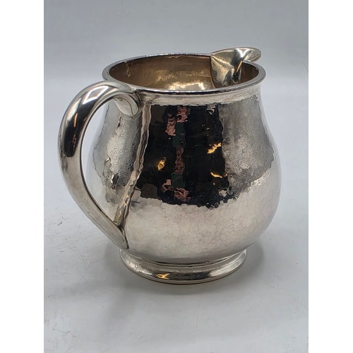 18 - Two matching sterling silver hand planished jugs together with matching hand planished sterling silv... 