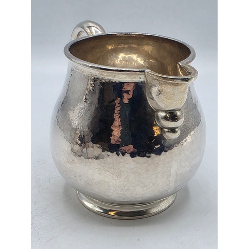 18 - Two matching sterling silver hand planished jugs together with matching hand planished sterling silv... 